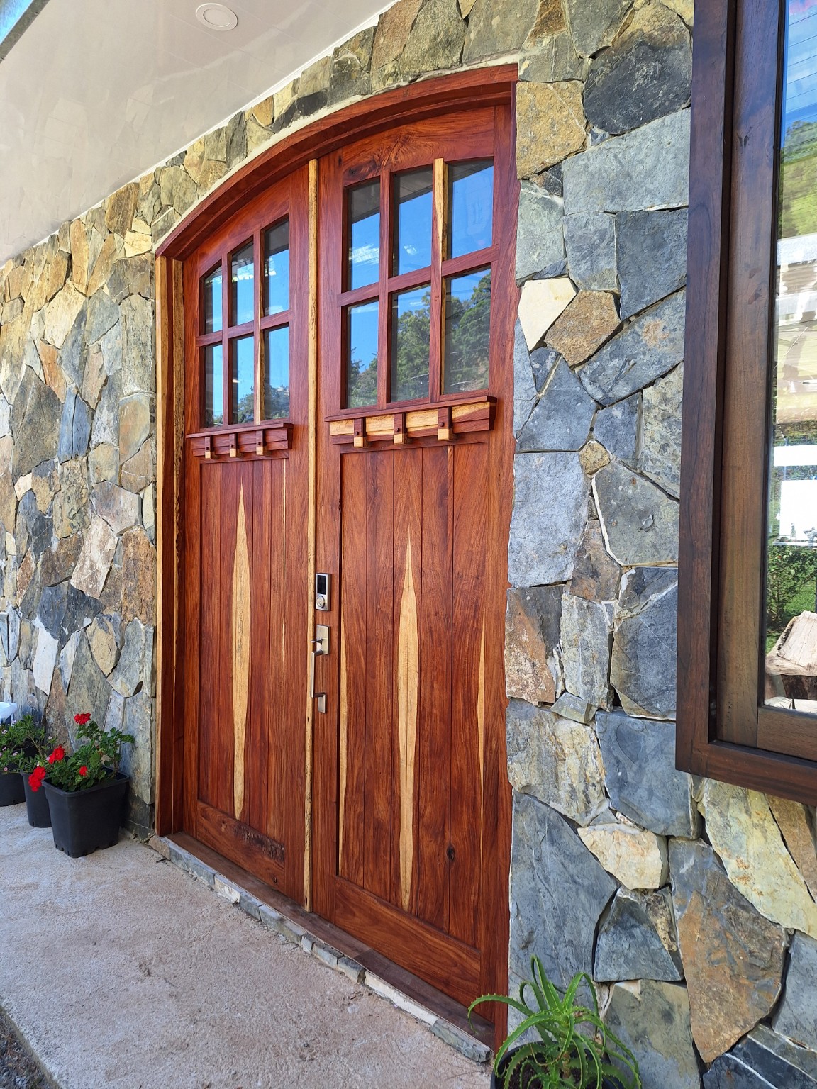 Puerta exterior de madera con detalles verticales, instalada en fachada de piedra